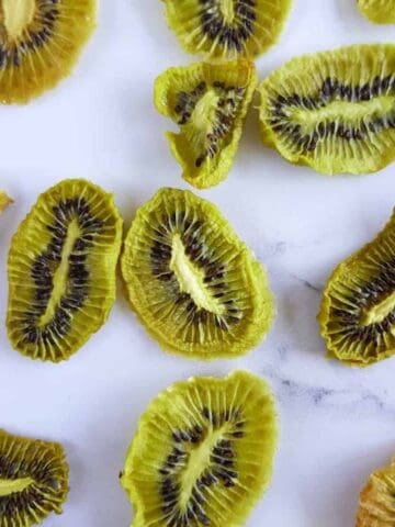 Dried kiwi slices on a marble table.