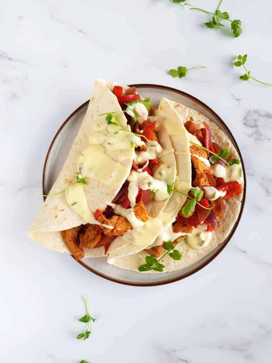 Fajitas with pork chops with sour cream sauce on a marble table.