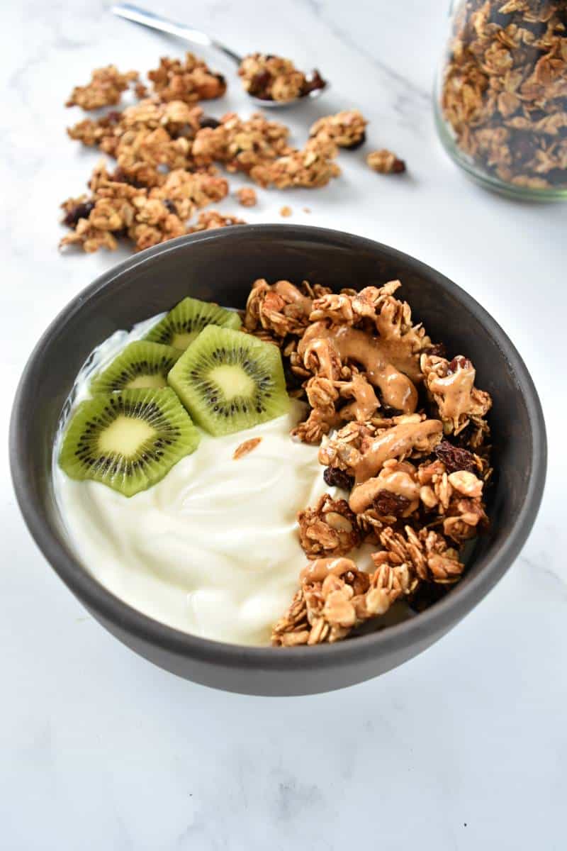 A bowl of yogurt, granola and sliced kiwi.