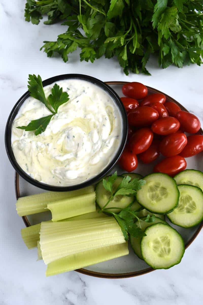 Greek tzatziki in a bowl with raw vegetables on the side.