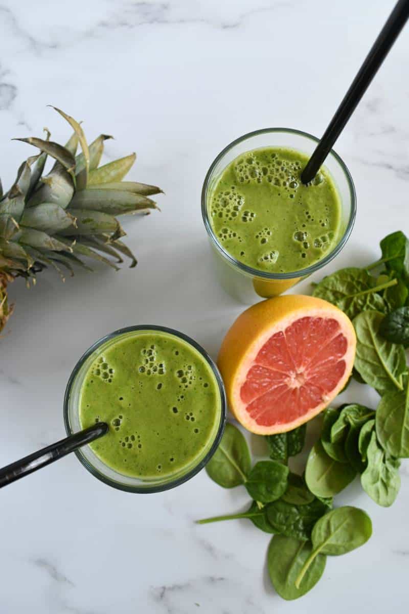 Green pineapple smoothie in glasses on a marble table.