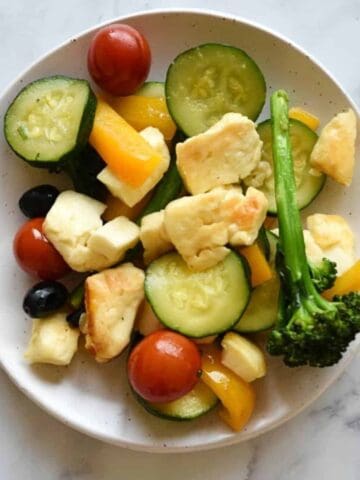 Halloumi stir fry on a white plate on a marble table.