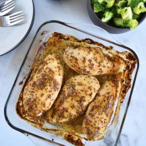 Honey mustard chicken in a casserole dish. on a marble table.