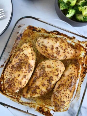 Honey mustard chicken in a casserole dish. on a marble table.