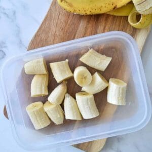 Banana bites in a container with banana peels on the side.