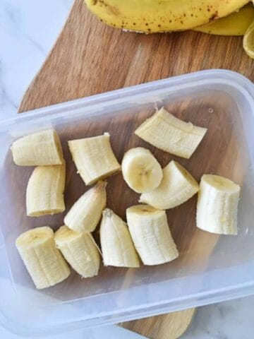 Banana bites in a container with banana peels on the side.