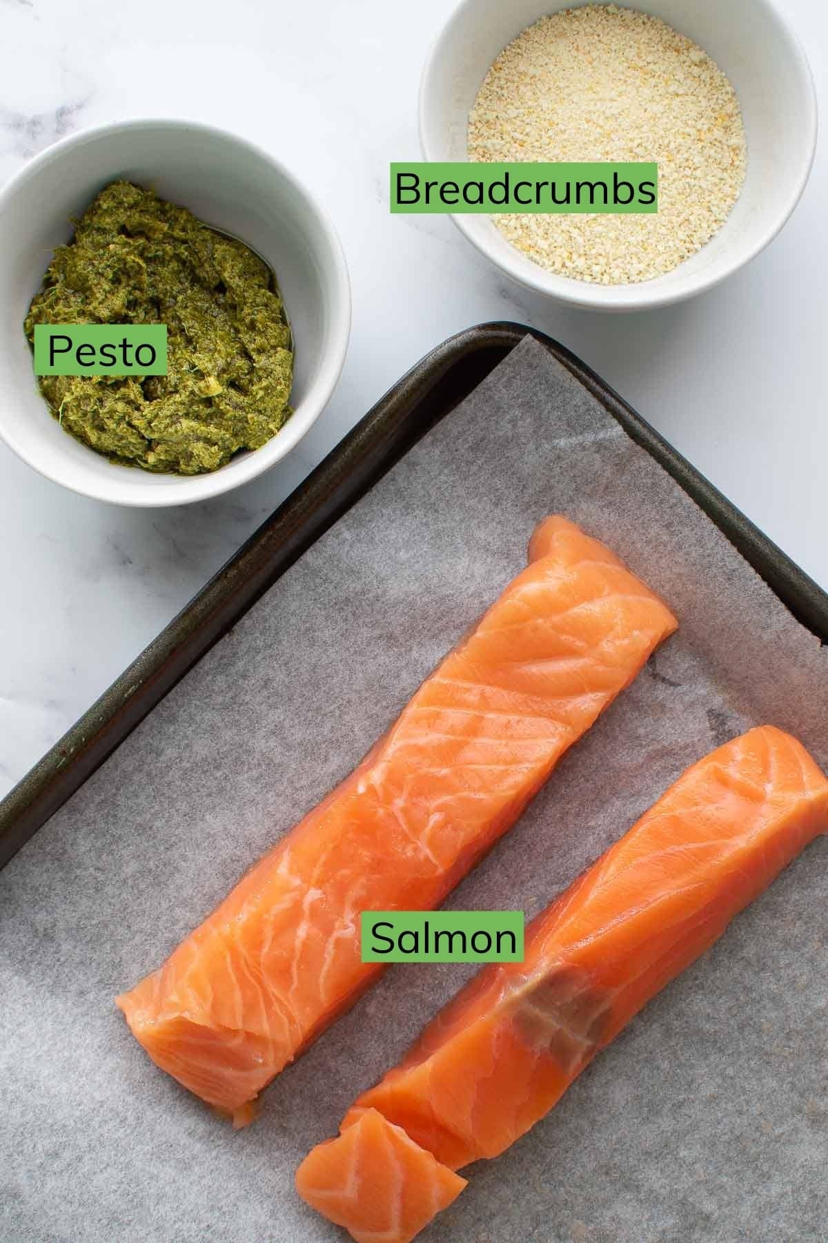 Salmon, pesto and breadcrumbs laid out on a table.