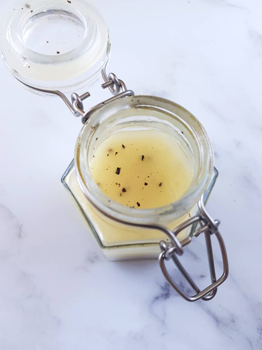 Lemon pepper vinaigrette in a jar on a marble table.