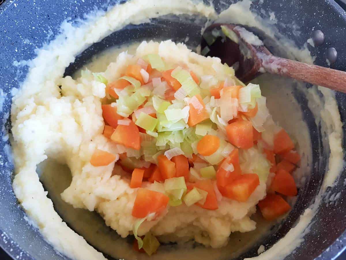 Mashed potatoes with carrots and leek in a pot.