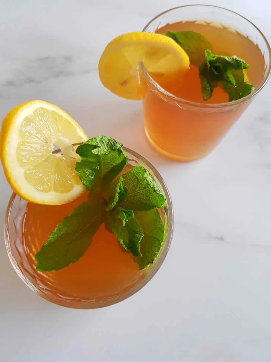 Mint iced tea in glasses with fresh mint and lemon wedges.