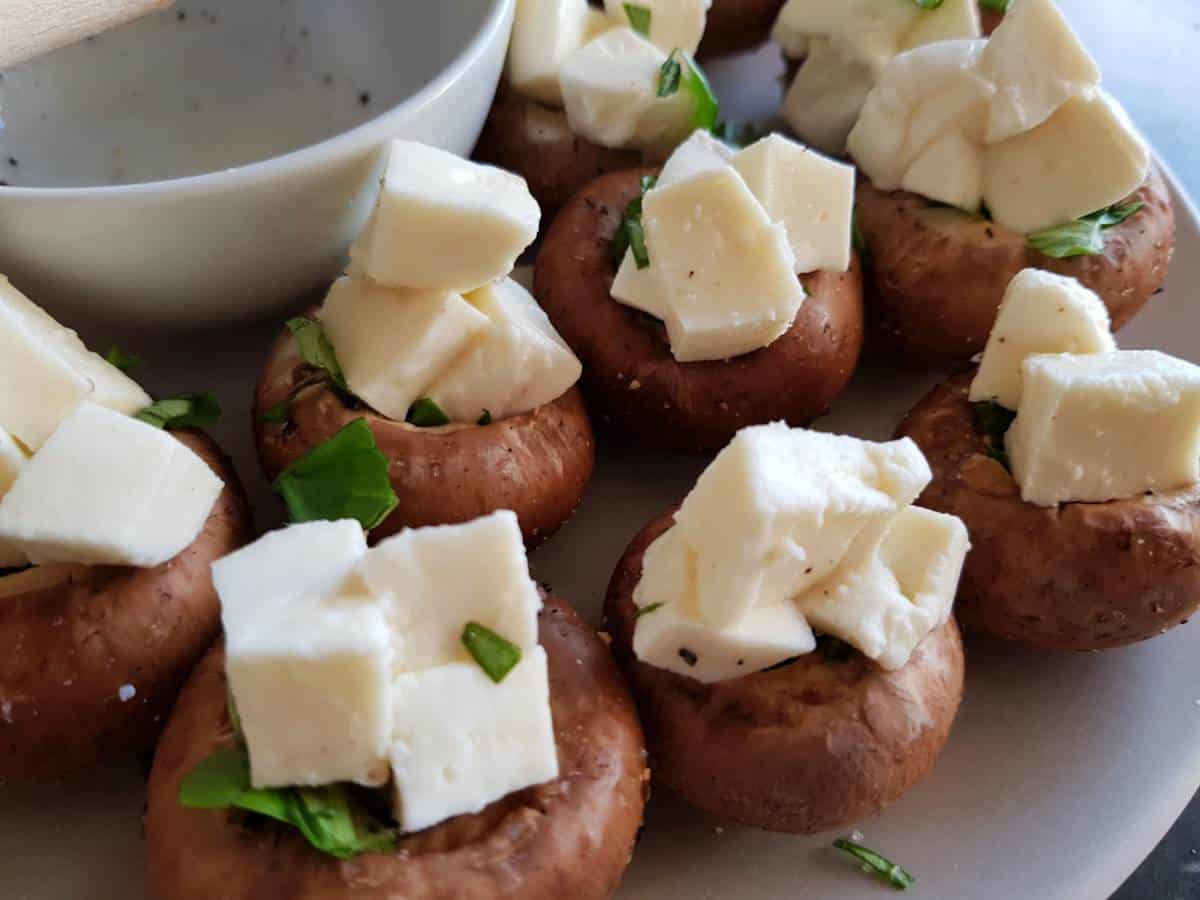 Mushrooms stuffed with mozzarella and basil on a plate.