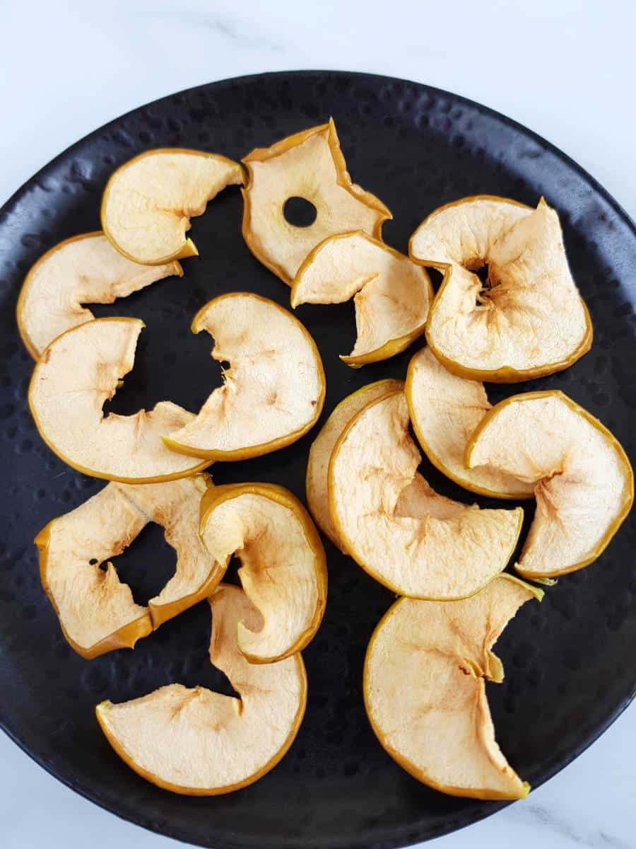 Oven baked apple slices on a black plate.