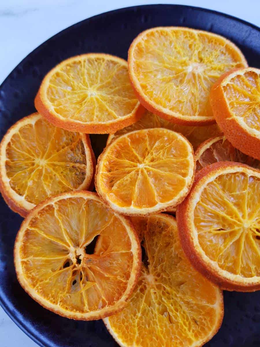 Dried orange slices on a black plate.