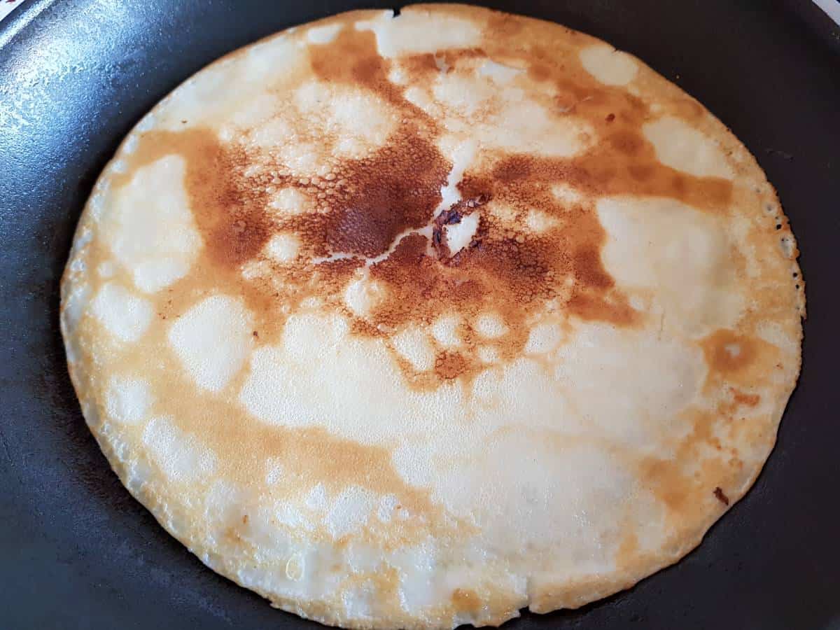 Pancakes frying in frying pan.