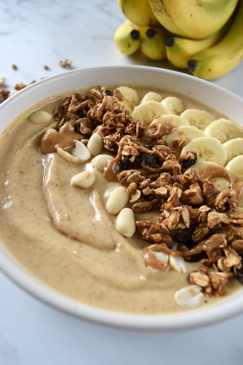 Peanut butter banana smoothie bowl with granola and sliced bananas.