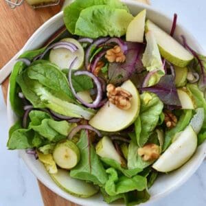 Pear and walnut salad with red onion in a bowl.