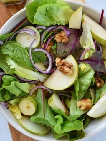 Pear and walnut salad with red onion in a bowl.