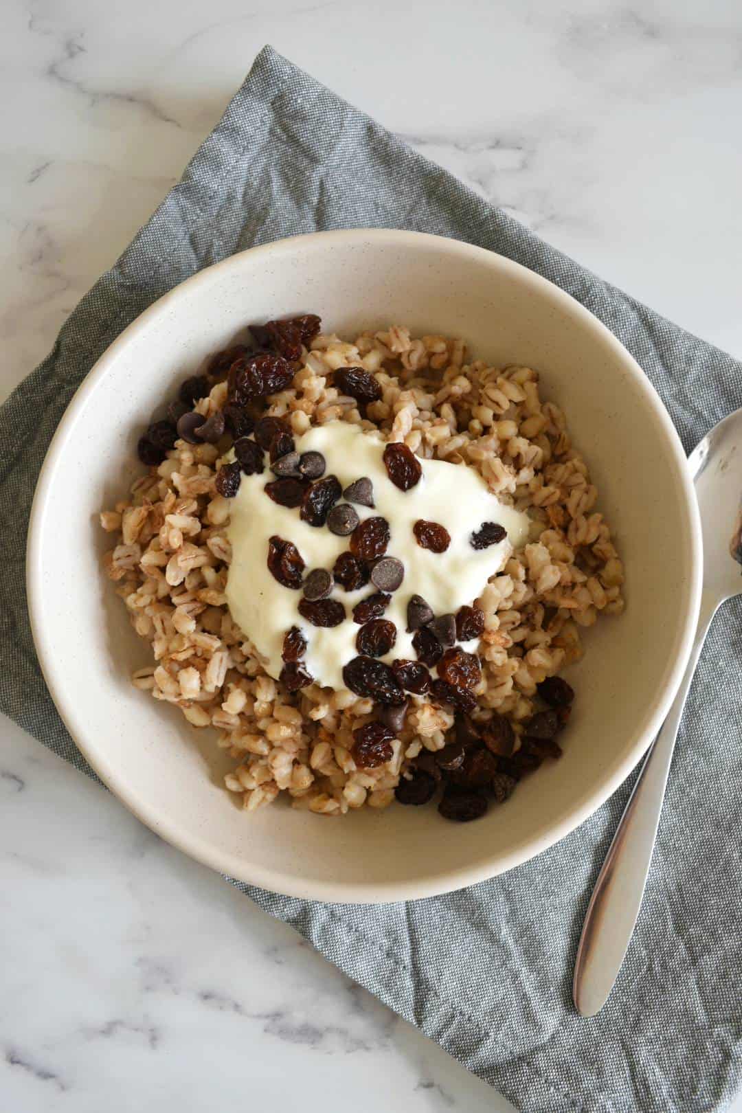 Barley porridge in a bowl with a spoon on the side.