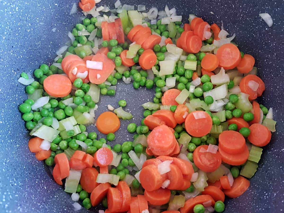 Peas and carrots in a pot cooking.