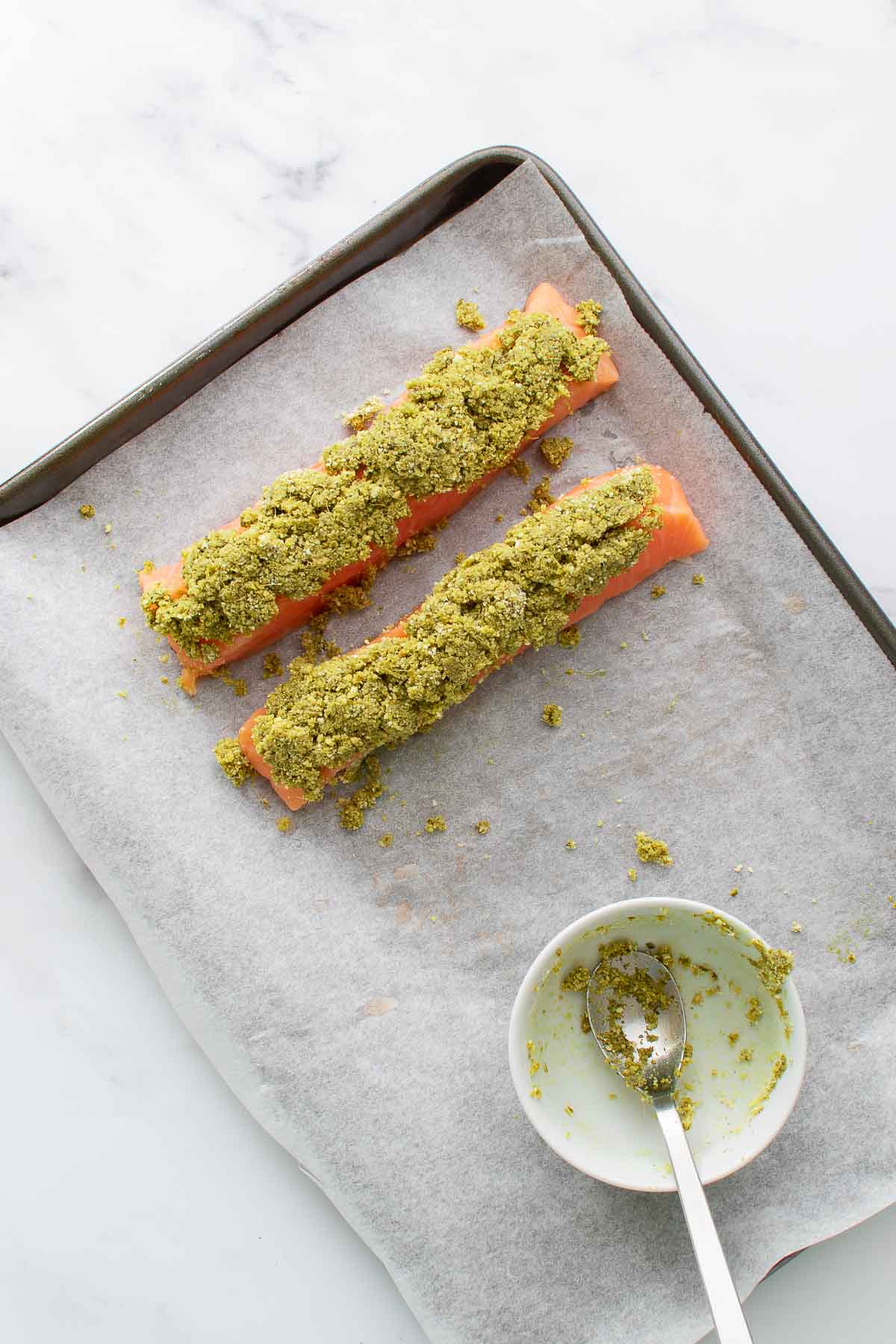 Salmon with pesto crust on a baking sheet.