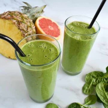 Pineapple grapefruit smoothie with fresh fruits and spinach on the side.