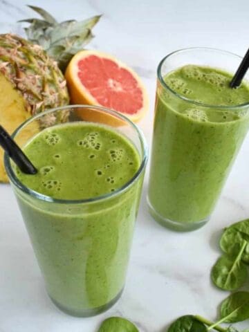 Pineapple grapefruit smoothie with fresh fruits and spinach on the side.