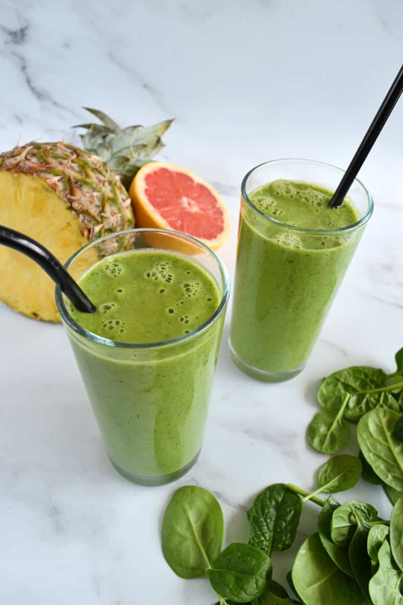 Pineapple grapefruit smoothie in glasses with black straws.