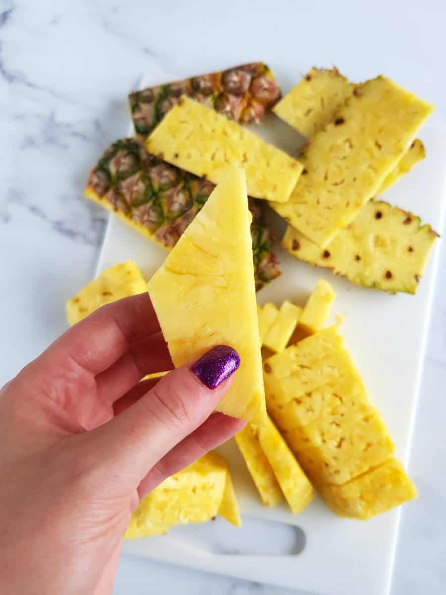 Hand holding a pineapple slice.