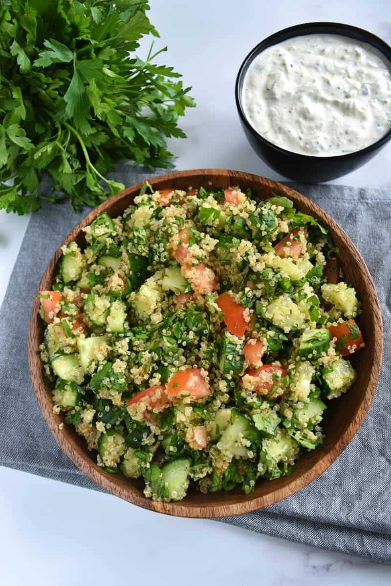 Quinoa tabbouleh with tzatziki and fresh herbs on the side.