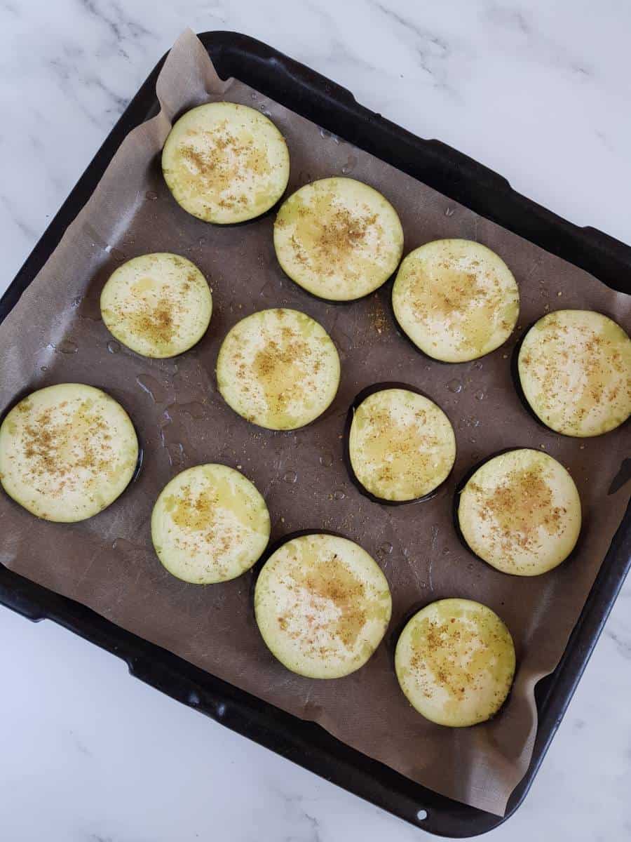 Raw eggplant slices on a baking sheet.