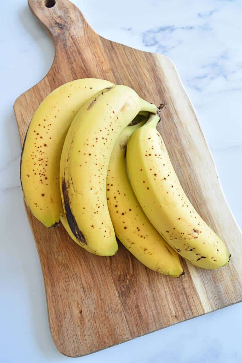 Ripe bananas on a wooden chopping board.