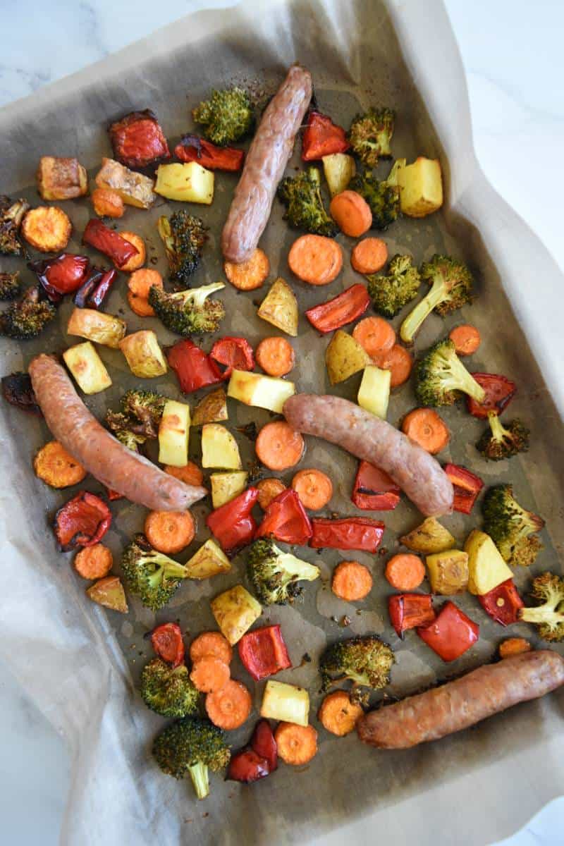 Sausages, broccoli, potatoes, carrots and peppers on a sheet pan.