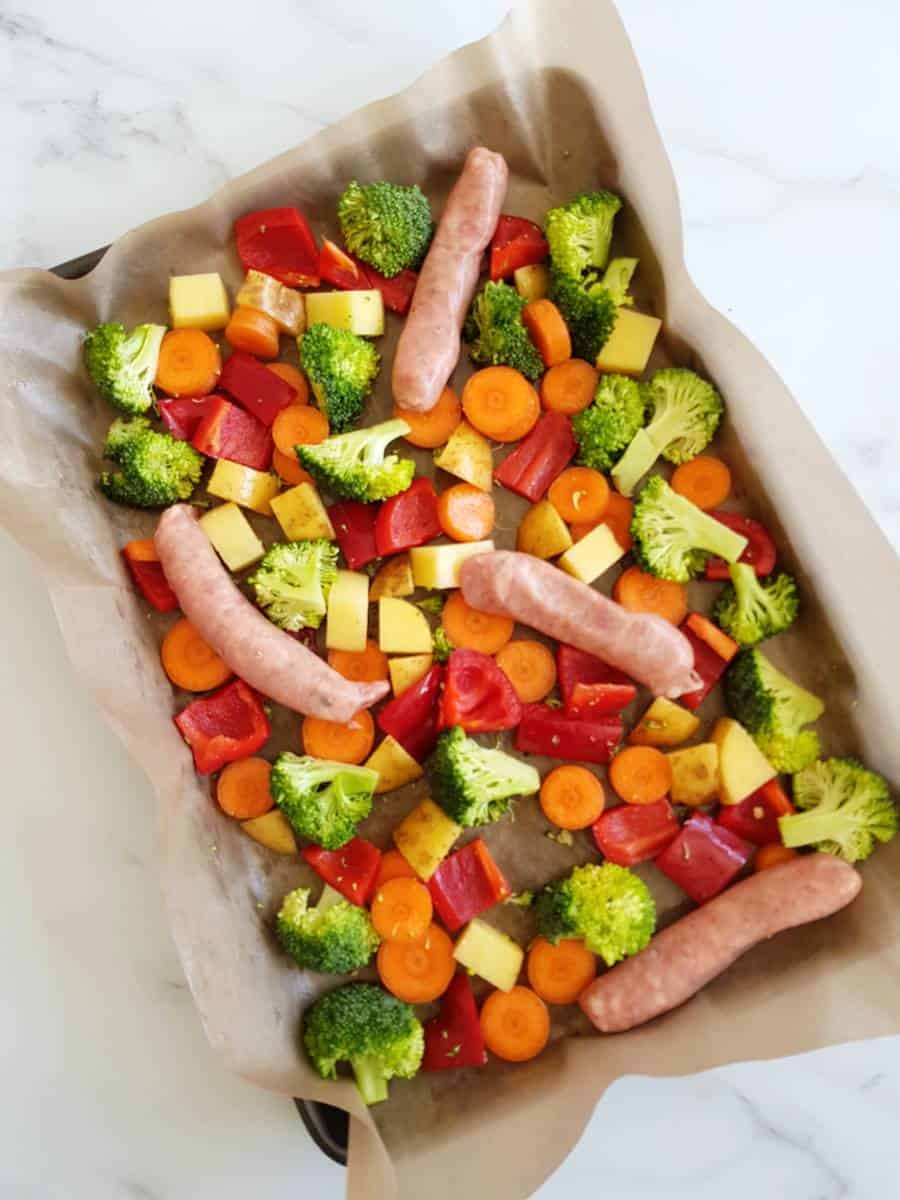 Sausages and vegetables on a sheet pan.