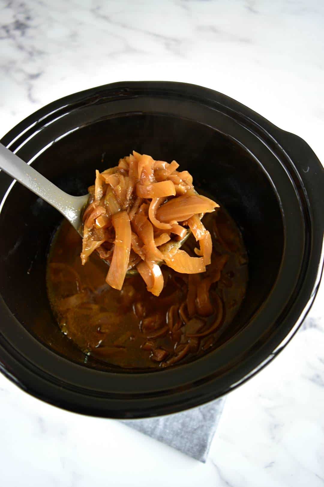 French onion soup being served from a slow cooker.
