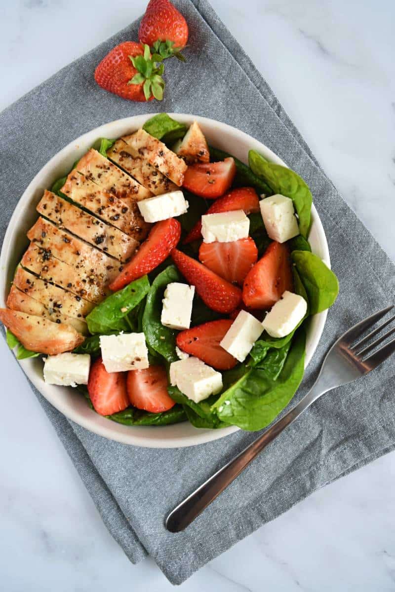 Strawberry spinach chicken salad in a bowl with a fork on the side.