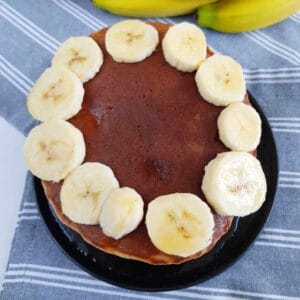 Banana pancakes stacked with bananas on top.