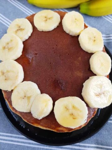 Banana pancakes stacked with bananas on top.