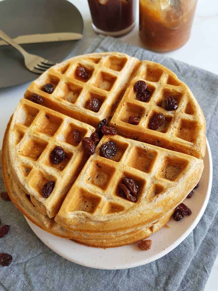 Waffles on a plate with raisins on top.