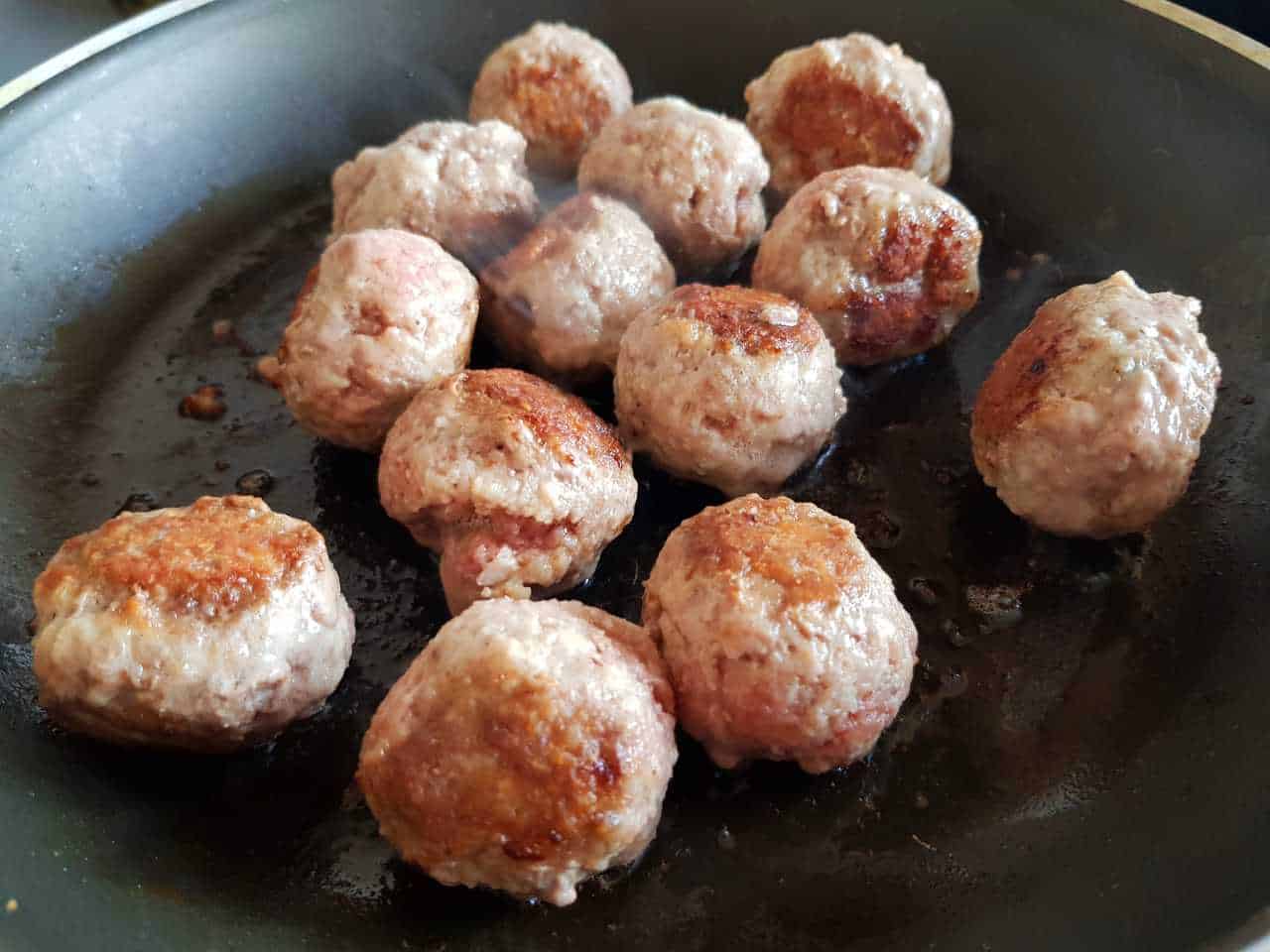 Meatballs cooking in a pan.