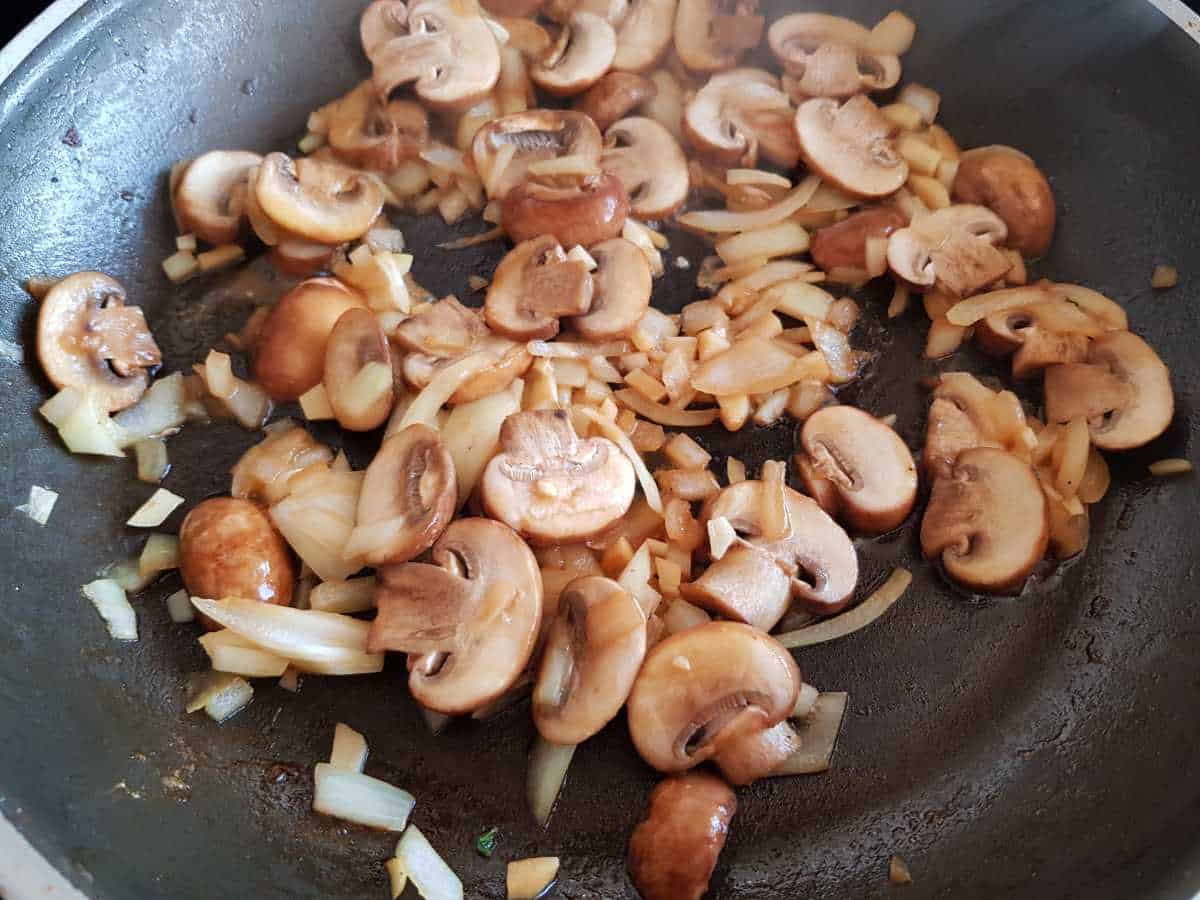 Mushrooms and onion in a pan.