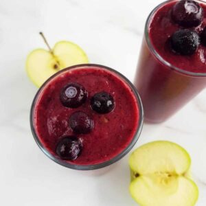 Apple blueberry smoothie with apples on a marble table.