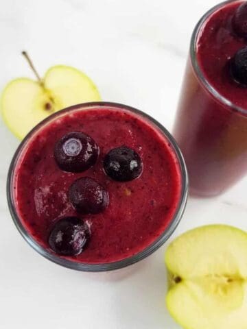 Apple blueberry smoothie with apples on a marble table.