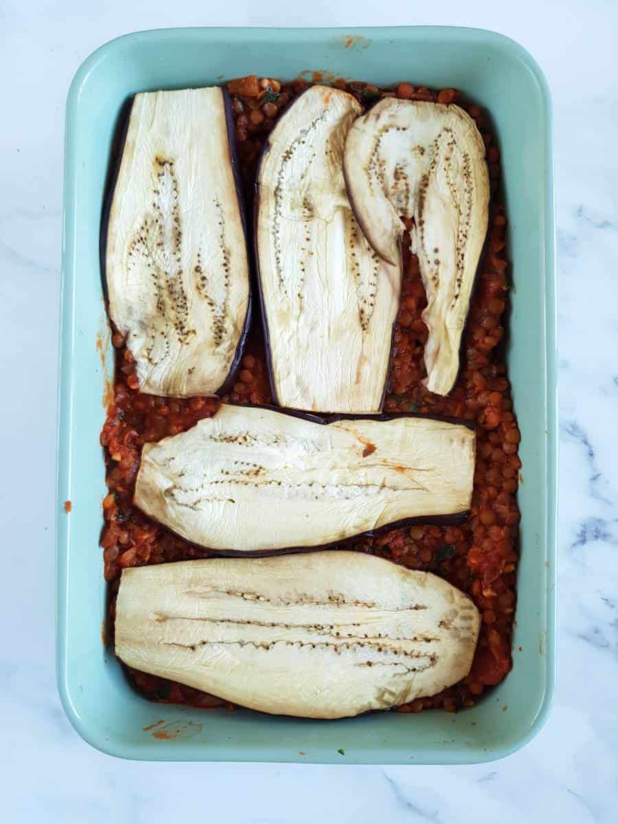 Aubergine slices over lentil tomato sauce in a casserole dish.