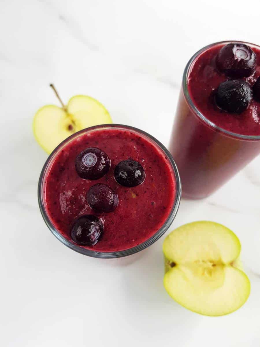 Blueberry and apple smoothie with fresh apples on the side.