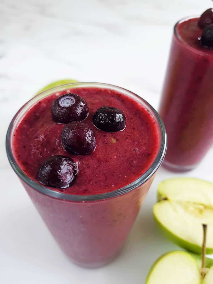 Blueberry apple smoothie in glasses on a marble table.