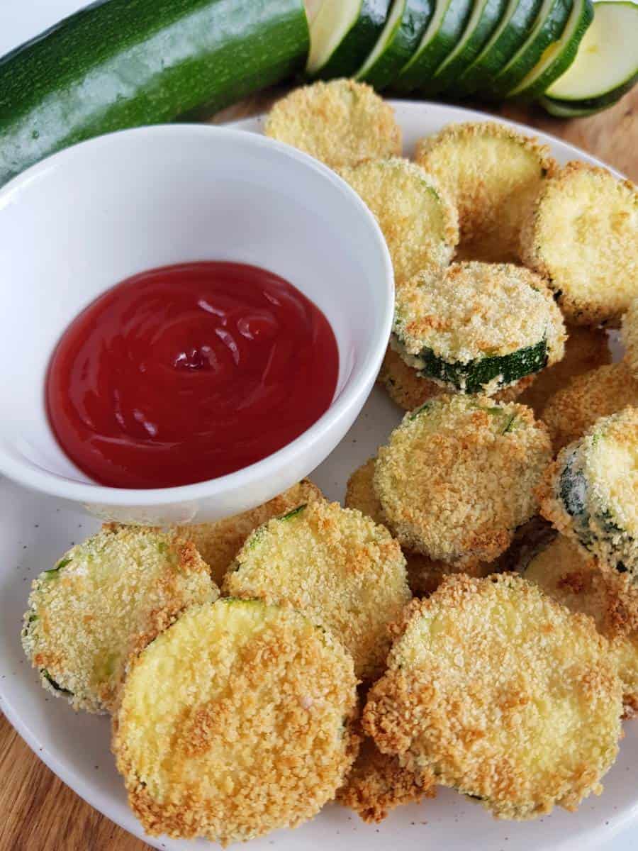 Crispy zucchini slices on a plate with ketchup.