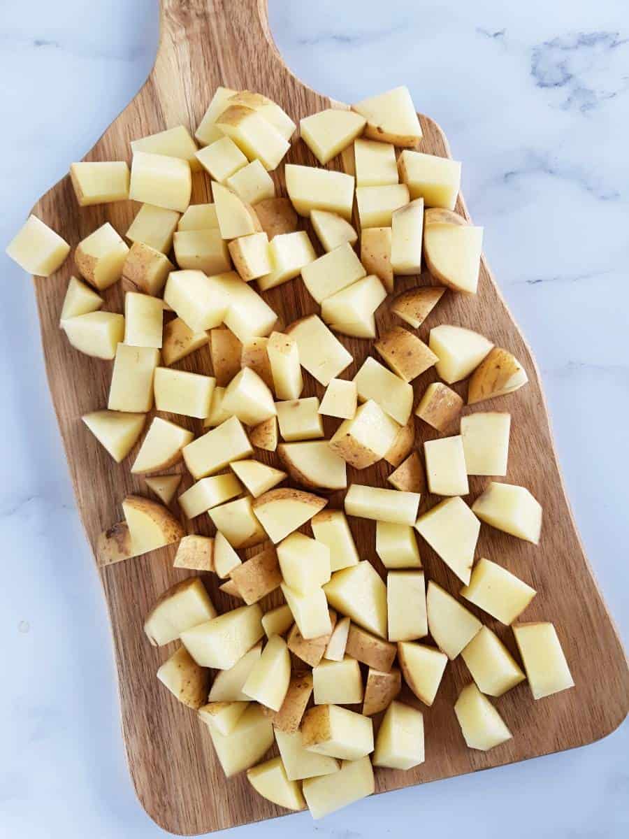 Cubed potatoes on a wooden chopping board.