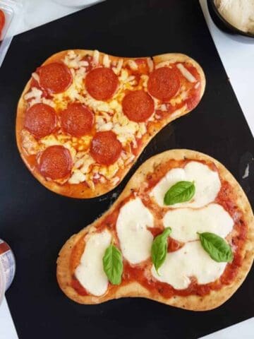 Naan bread pizzas on a baking sheet.