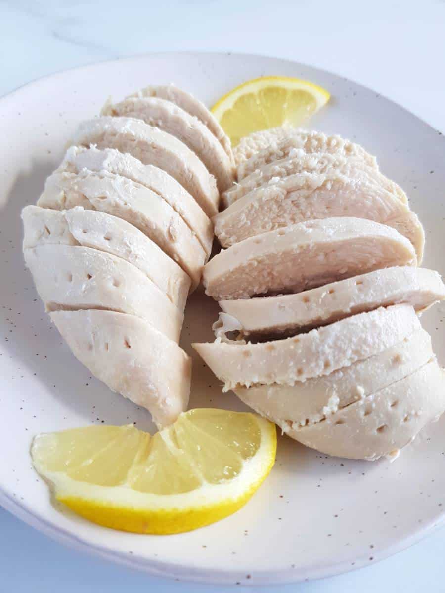 Poached chicken breasts on a plate.