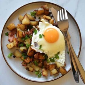 Pyttipanna on a plate with cutlery on the side.